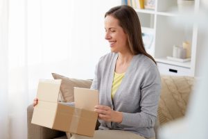 smiling woman opening parcel box at home